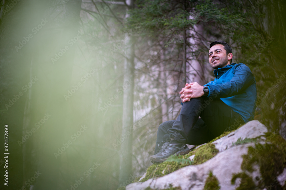 Experienced hiker sitting on rock taking a break from hiking Experienced hiker sitting on rock taking a break from hiking