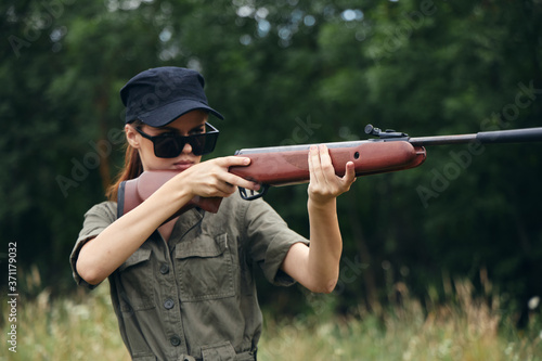 Military woman hunting with shotgun sunglasses green leaves 