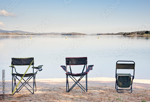 Beautiful couple landscape of a picturesque lake at sunrise with three chairs waiting to be used © mestock