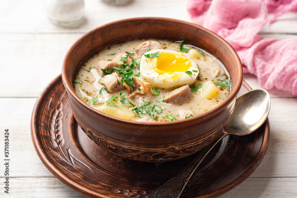 Traditional Polish sour soup Zurek in ceramic bowl on rustic wooden background Traditional Polish sour soup Zurek in ceramic bowl on rustic wooden background
