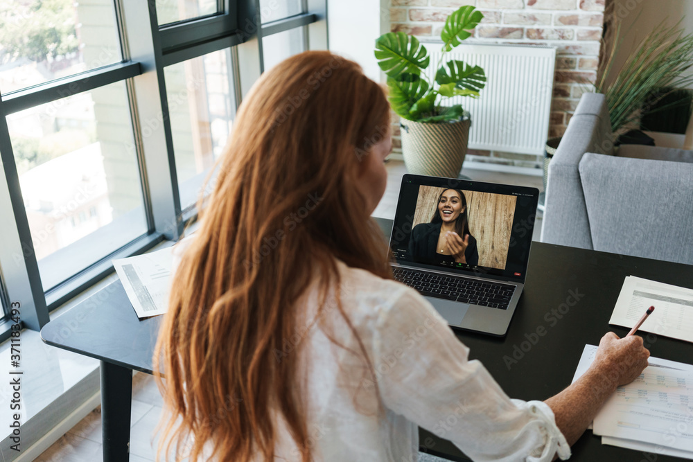 Image of businesswoman making call on laptop while sitting at table Image of businesswoman making call on laptop while sitting at table