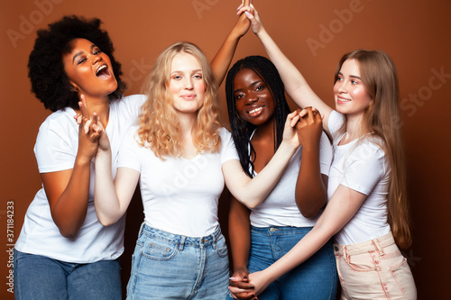 young pretty caucasian, afro, scandinavian woman posing cheerful together on brown background, lifestyle diverse nationality people concept