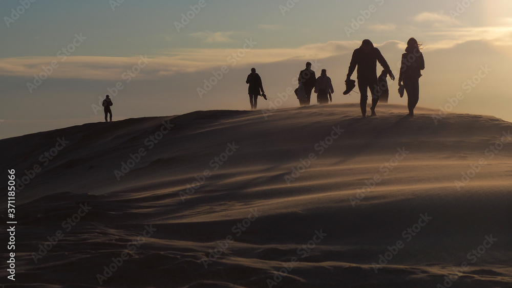 Silhouettes de personnes marchant sur la Dune du Pilat, en contre-jour