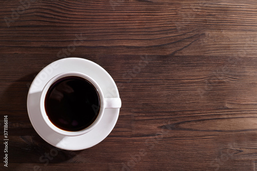 A cup of coffee on wooden table. Background with copy space.