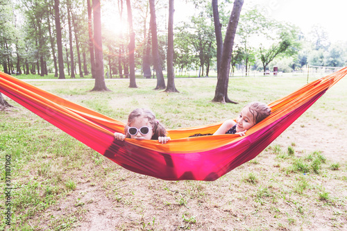 Happy little girls relax on hammock in nature