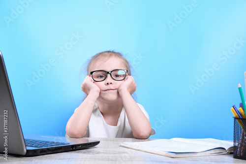 Back to school .Happy cute industrious child is sitting at a desk indoors. Kid is learning in class in home with laptop, computer
