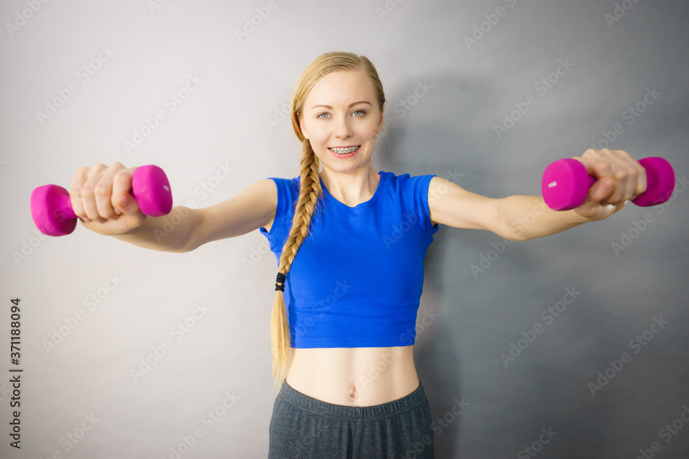 Teenage woman working out at home with dumbbell Teenage woman working out at home with dumbbell