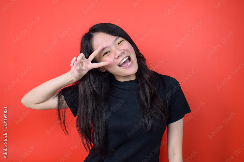 Portrait of Young beautiful asian woman using black T-shirt with red isolated background Portrait of Young beautiful asian woman using black T-shirt with red isolated background