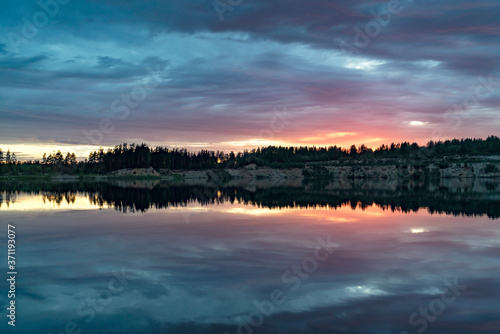 Colorful sunset with a mirror reflection in a forest lake . © amarinchenko106
