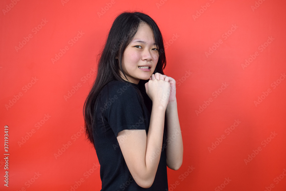 Portrait of Young beautiful asian woman using black T-shirt with red isolated background Portrait of Young beautiful asian woman using black T-shirt with red isolated background