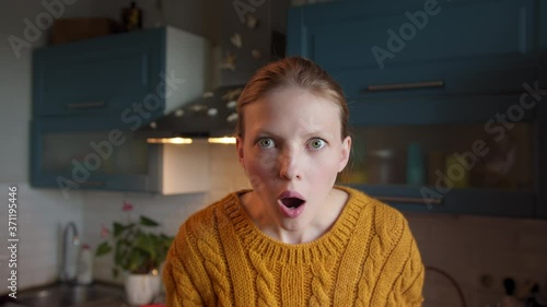 Portrait beautiful young woman looking shocked surprise at camera in modern kitchen