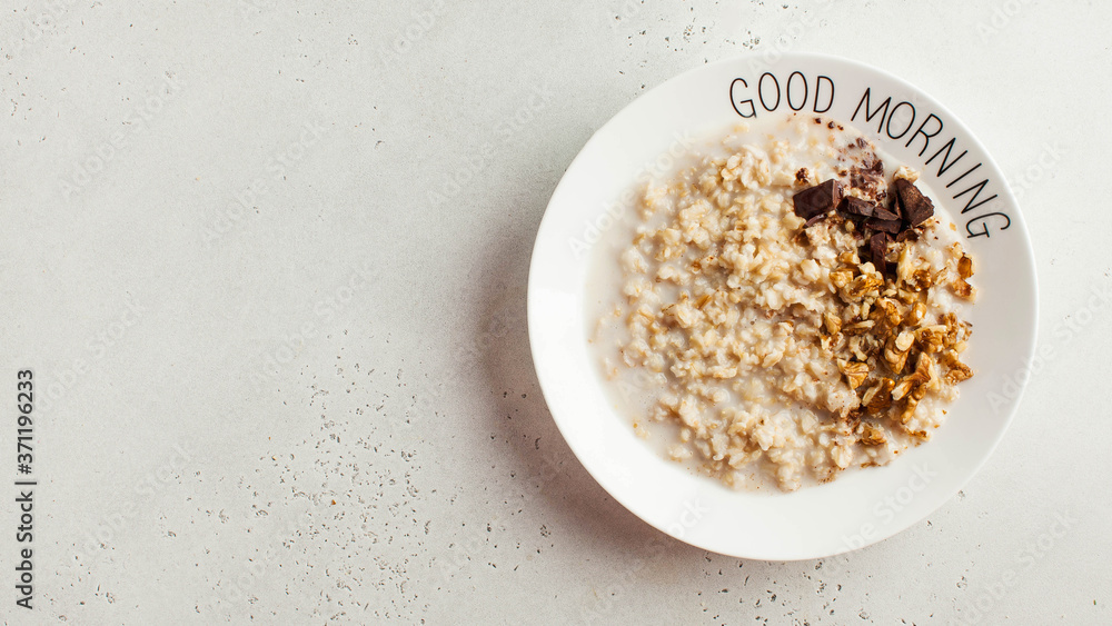Banner oatmeal porridge with chocolate and nuts on a plate that says good morning. Healthy food, Breakfast. Copy space. Banner oatmeal porridge with chocolate and nuts on a plate that says good morning. Healthy food, Breakfast. Copy space.