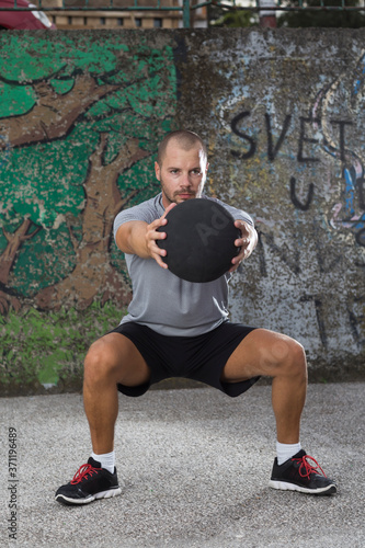 Sportist working out with a medicine ball outdoors. photo