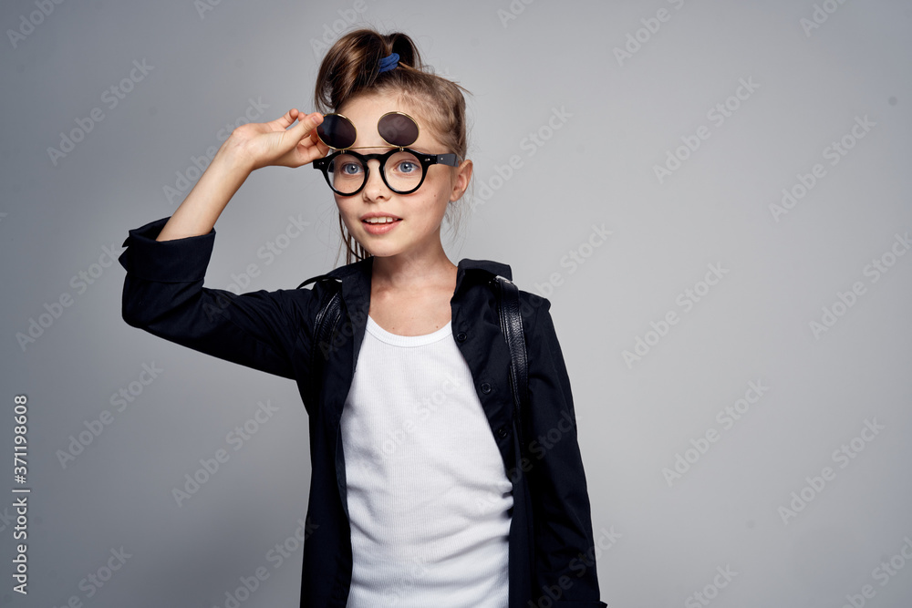 Cute schoolgirl wearing sunglasses childhood learning school light background