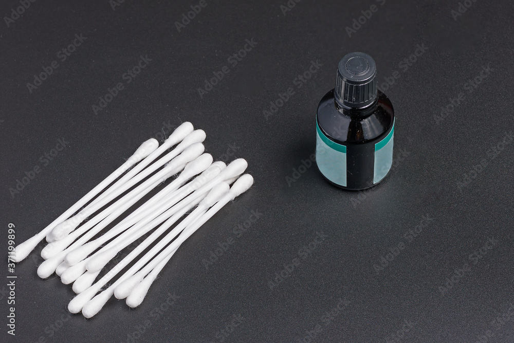 Naklejka premium Top view of cotton swabs and a bottle of antiseptic on a black background close up