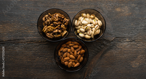 Almond, pistachio and walnut in a small plates which standing on a black table. Nuts is a healthy vegetarian protein and nutritious food.