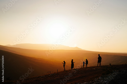 Silhouettes of people at sunset. Beautiful fiery sunset. People admire the sunset