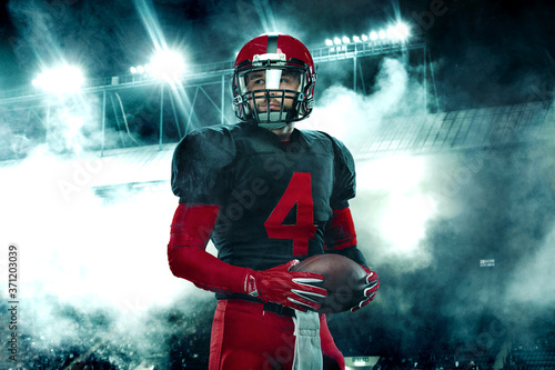 Closeup portrait of american football player, athlete sportsman in red helmet on grand arena background. Sport and motivation wallpaper. © Mike Orlov