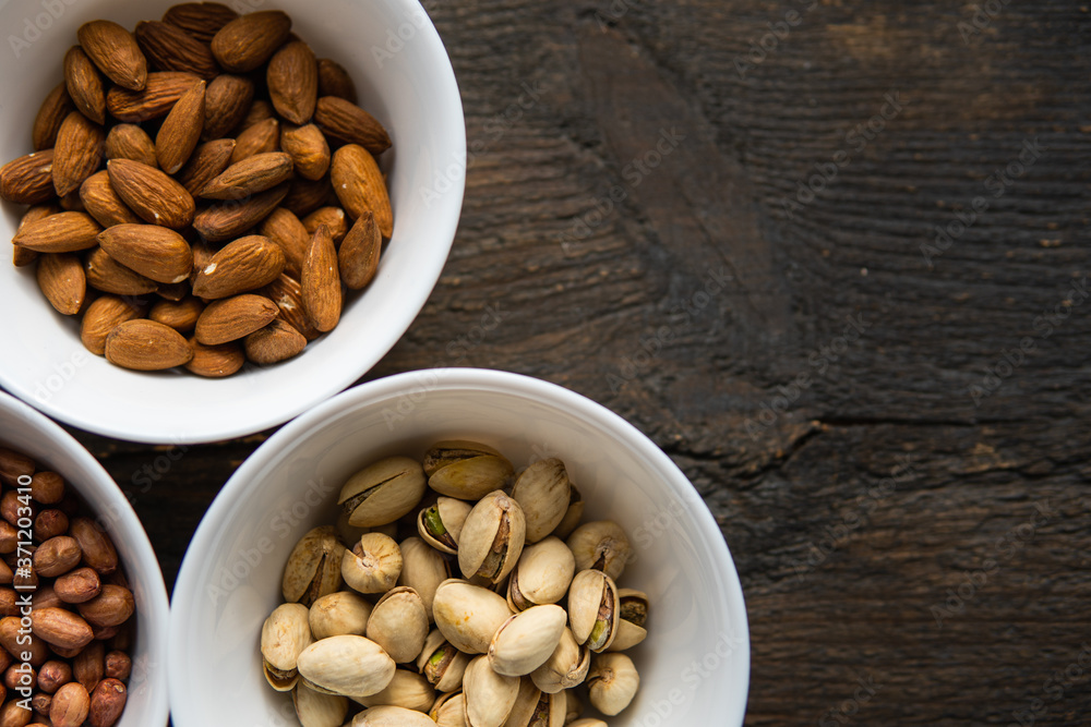 Pistachio, peanut and almond in a small plates which standing on a black table. Nuts is a healthy vegetarian protein and nutritious food. Pistachio, peanut and almond in a small plates which standing on a black table. Nuts is a healthy vegetarian protein and nutritious food.