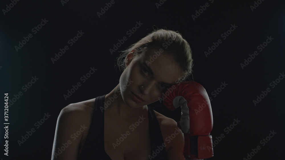 Young woman posing with red boxing gloves on black background in studio Young woman posing with red boxing gloves on black background in studio