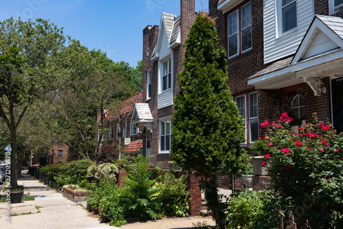 Row of Beautiful Homes with Gardens in Sunnyside Queens New York along the Sidewalk during Summer © James