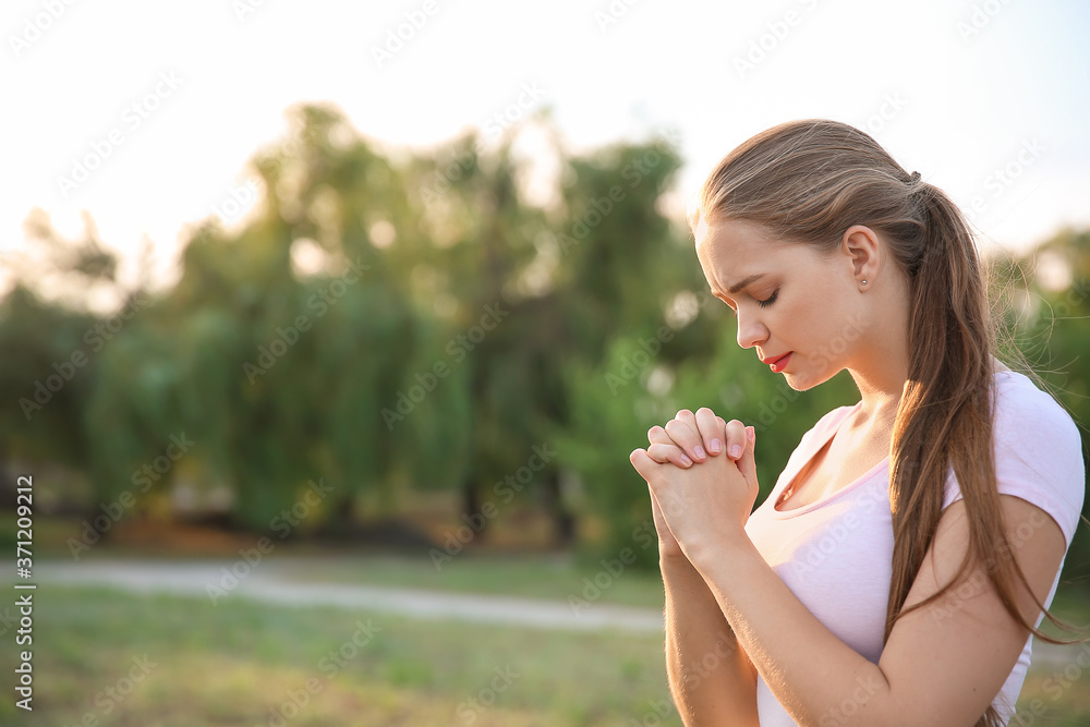 Young woman praying to God outdoors