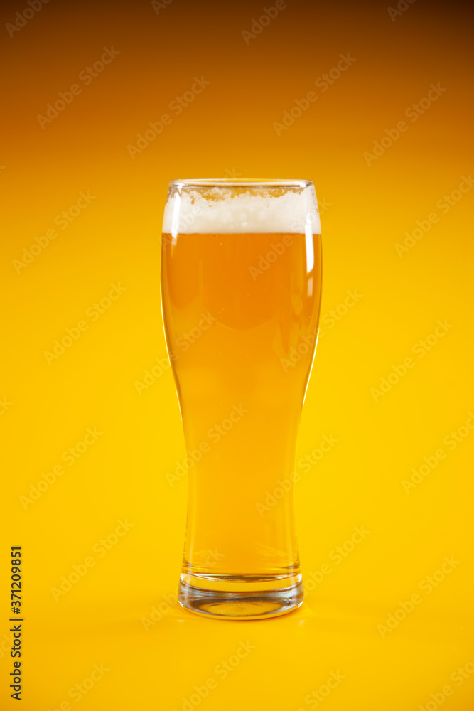 Glass of beer with foam on orange background Glass of beer with foam on orange background