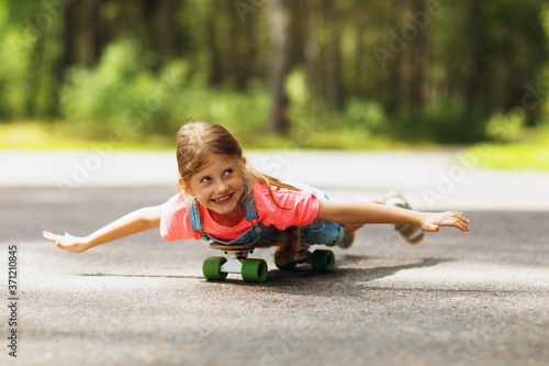 Happy child is riding a skateboard in the park on a sunny summer morning