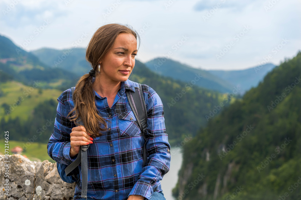 Portrait of Beautiful woman with backpack and blue shirt. Enjoying nature that surround her.