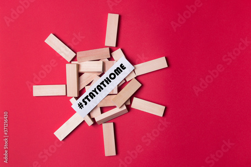 jenga wooden blocks with copyspace and #stay at home on red colored background