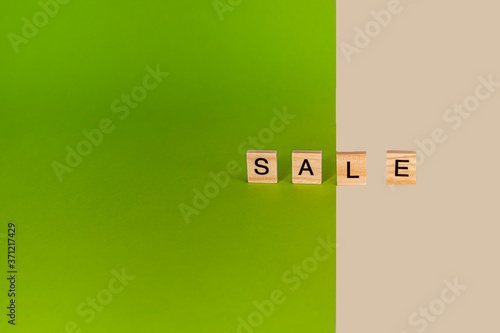 Inscription sale from wooden cubes on colored, yellow and green cardboard.