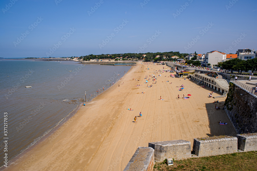 The main beach of the town of Fouras in Vendée. The morning is starting and there are not many bathers on the sand yet. A few clouds in the blue sky.