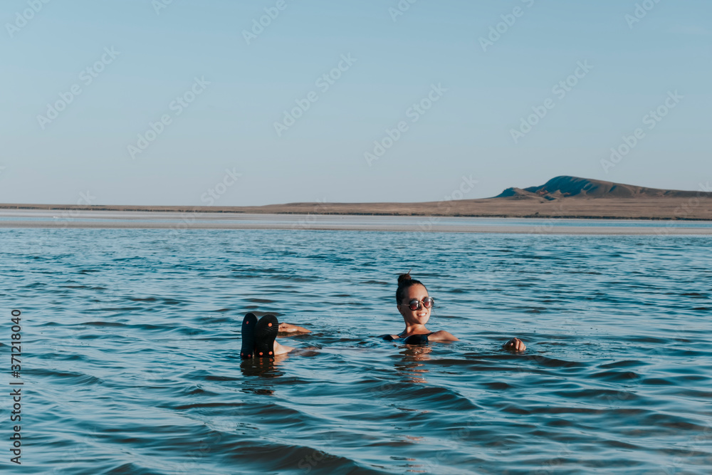 Photo of a woman swimming in a salt lake against a background of mountains.