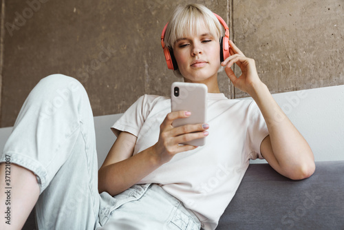 Blonde woman using mobile phone and listening music