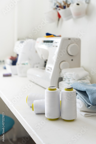 Sewing: several large skeins of white thread for sewing machines on the tailor's desk.