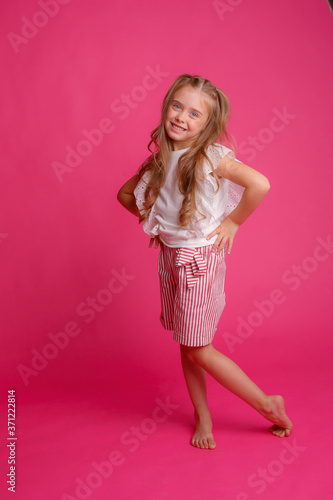 cute girl with long hair posing on a pink background in the Studio