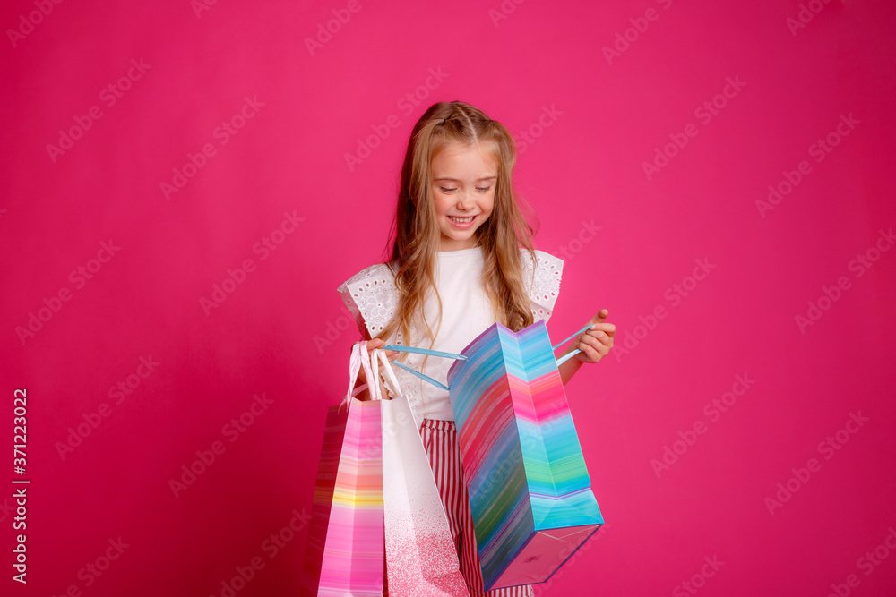 a little Girl with a lot of shopping bags on a pink background in the Studio, happy a little Girl with a lot of shopping bags on a pink background in the Studio, happy