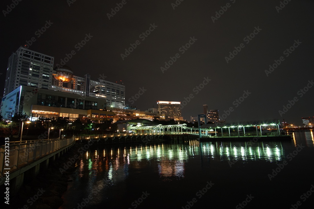 road of walkway in odaiba park at night with harbour and cityscape light of tokyo