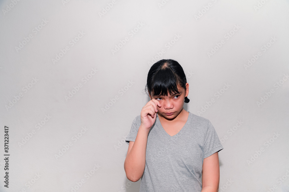 That girl hurt her eyes., Asian teen girl pain, sore eyes, touching with fingers or rubbing the eyes, she feels eye pain, there may be foreign objects in the eyes Against a gray background That girl hurt her eyes., Asian teen girl pain, sore eyes, touching with fingers or rubbing the eyes, she feels eye pain, there may be foreign objects in the eyes Against a gray background
