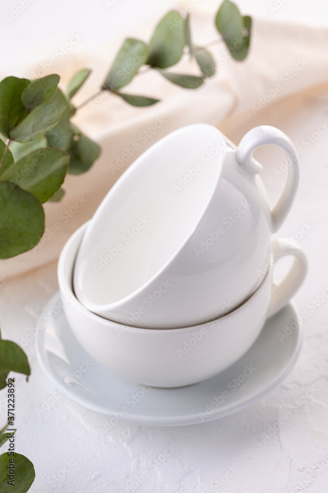 two empty white cups on a white table two empty white cups on a white table