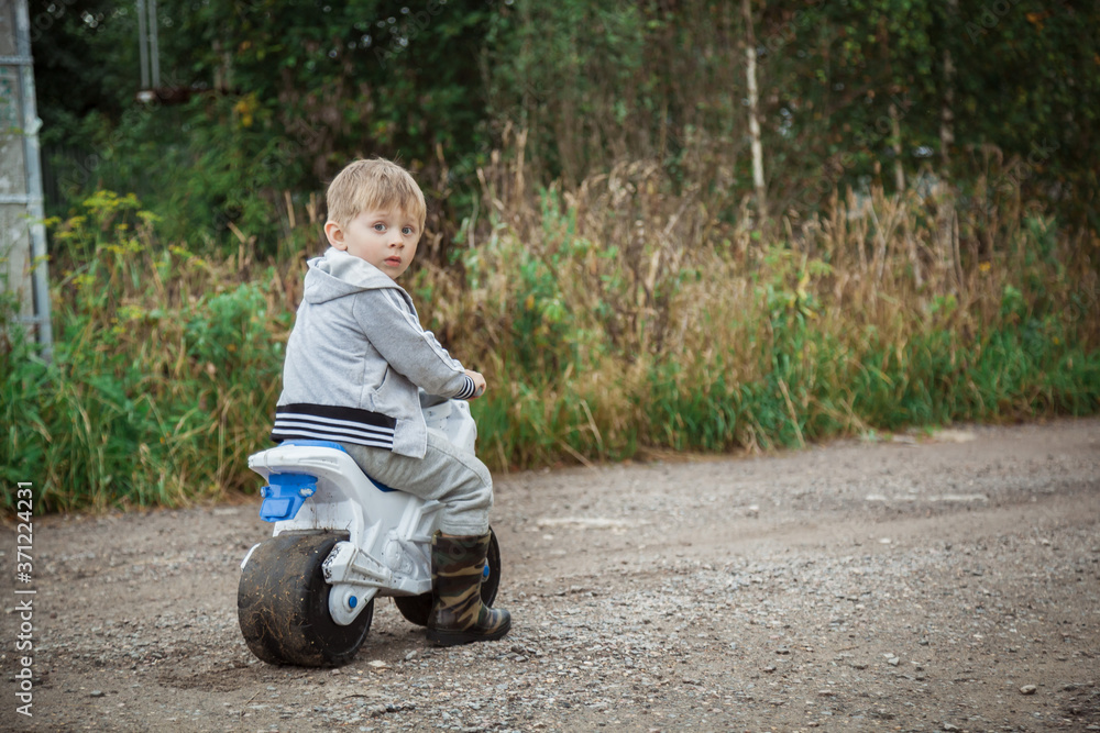 A little boy on a racetrack on a country road. A boy rides along a forest road. A little boy on a racetrack on a country road. A boy rides along a forest road.