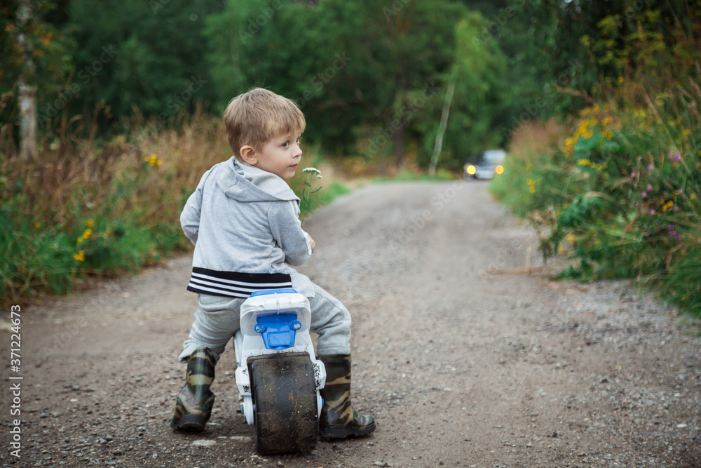 A little boy on a racetrack on a country road. A boy rides along a forest road. A little boy on a racetrack on a country road. A boy rides along a forest road.