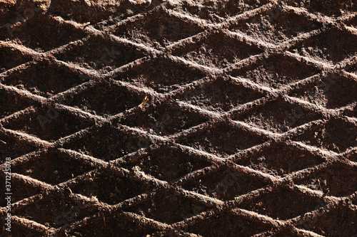 Canal cover surface texture. Rusty iron square pattern. Rusty metal square texture. Robust old iron rusted canal cover wallpaper. Ruststained canal grid form cover backdrop. photo