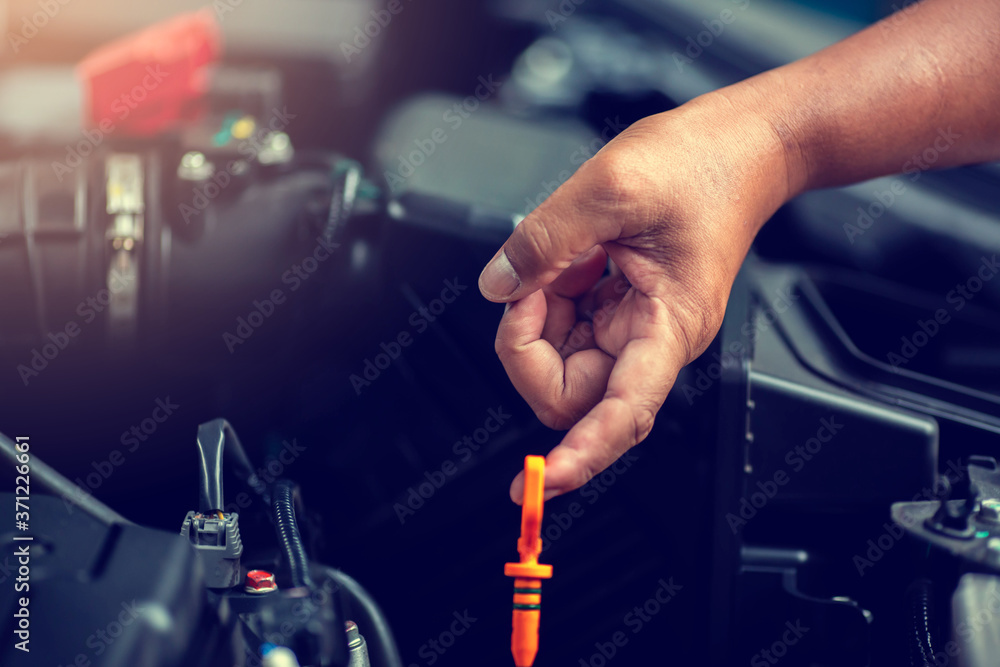 Selective focus to hand is checking the oil level in car engine.  Mechanic checking car engine or vehicle. Check and maintenance car with yourself. Service and maintenance vehicle.