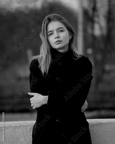 Obraz na płótnie Young brunette woman at the black coat posing at the city w salonie