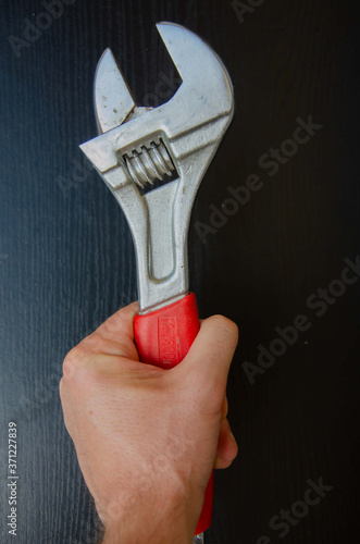 Wrench in hand. The master holds a metal key for repairing plumbing.