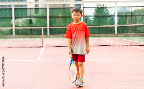 One lovely Asian boy is playing the tennis in the outdoor court with fun. Healthy kid with the exercise activity. © Natcharlai