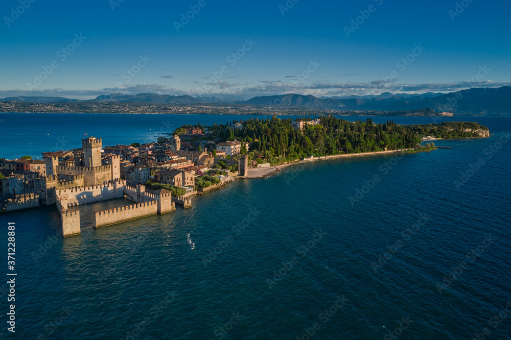 Panoramic aerial view early in the morning, Sirmione, an ancient village on southern Garda Lake, Italy. View by Drone. Rocca Scaligera Castle in Sirmione.