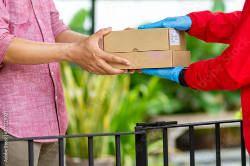 A courier in a red uniform is delivering a parcel to the landlord.