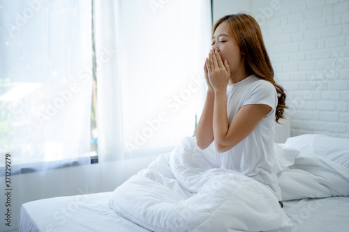 Asian woman wakes up in the morning. She yawned after waking up.